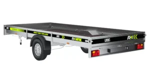 El remolque de embarque RX435i es un remolque utilitario de un eje con plataforma plana, laterales metálicos, la marca Lorries RX en negro y amarillo y conjunto de luces traseras, que se muestra sobre fondo blanco.